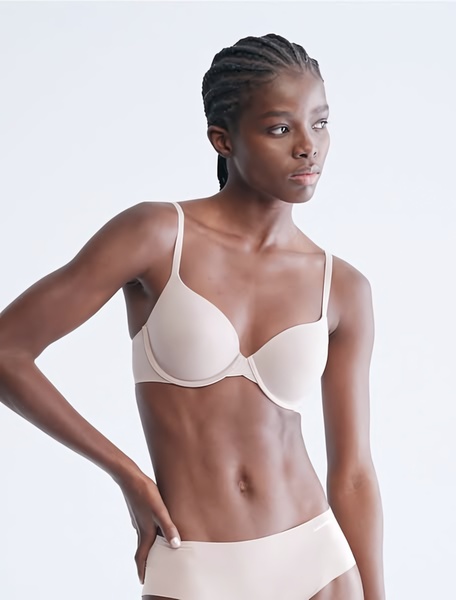 A clean, high-contrast studio photograph featuring a model wearing a neutral-toned underwire bra, focusing on fit and product clarity.